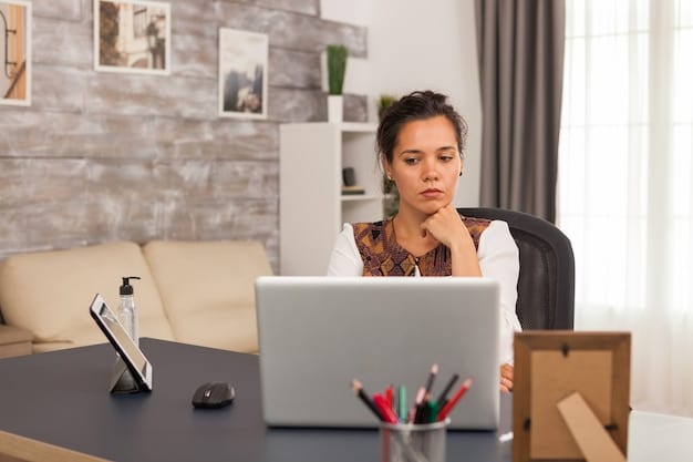 A person sitting at a desk, working on a laptop, with a concerned expression, representing the challenges of finding and applying for housing assistance.