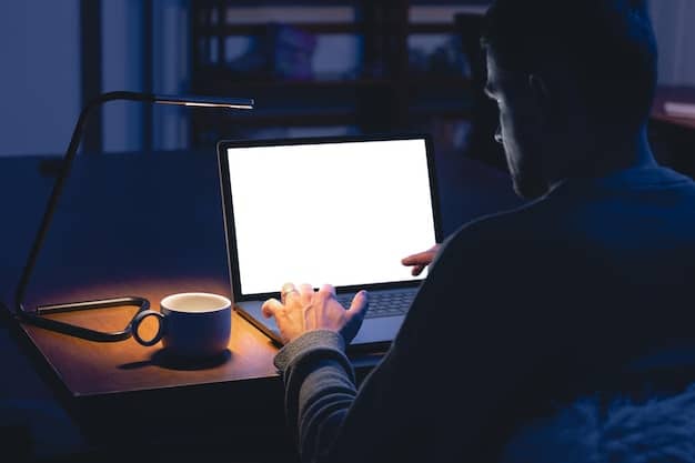 A person sits at their desk, illuminated by a laptop screen. They are working from home, focusing intensely on their task. This represents the flexible nature of the gig economy and telecommuting trend.