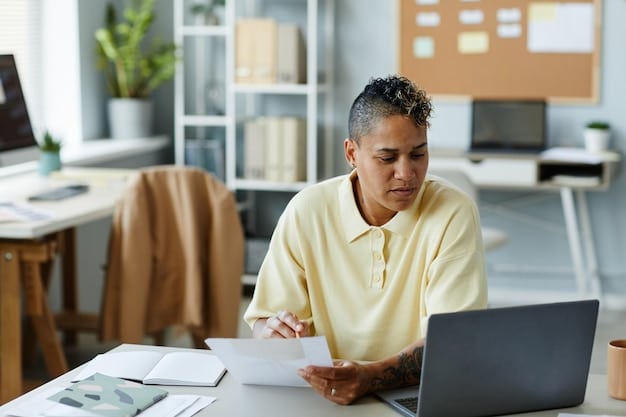 A person sitting at a desk, reviewing documents related to student loans and eligibility requirements. A laptop displays information about federal student loan forgiveness programs.