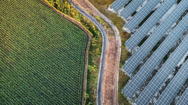 Aerial view of a solar panel field with wind turbines in the background, set against a sunset. This illustrates the energy sector investments for green initiatives aspect of analyzing the impact of the Infrastructure Bill on the construction industry and related investments.