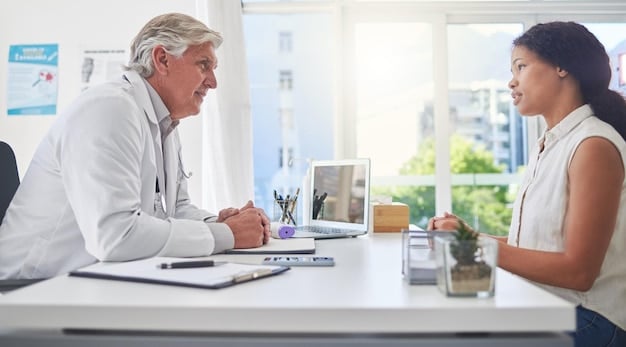 A doctor is sitting at a desk, explaining something to a patient on the other side of the desk.